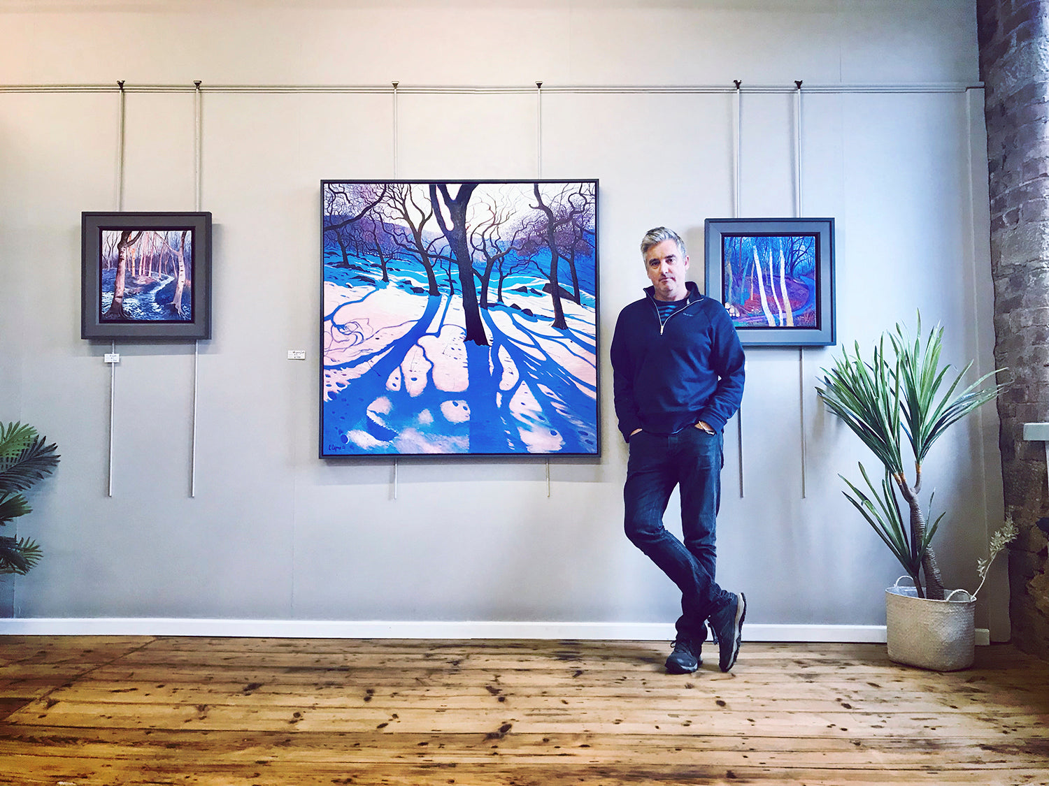 Chris stands in his studio with Original Painting 'whispering souls' © 2021
