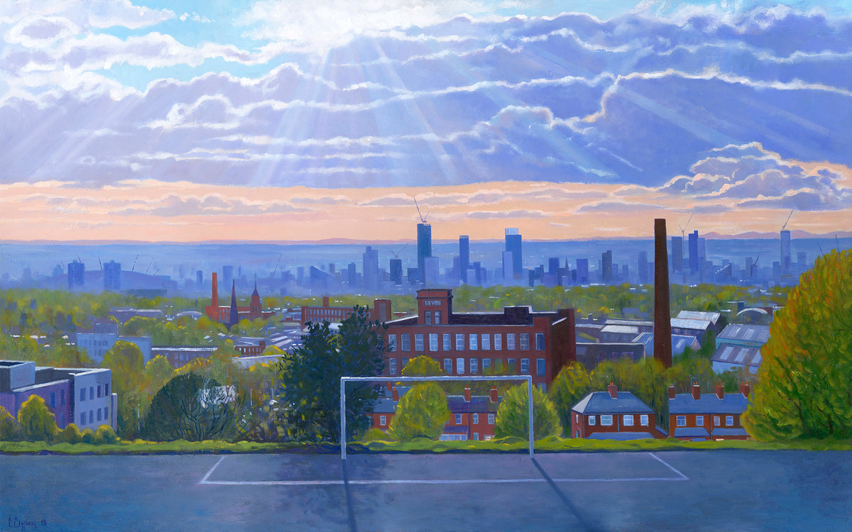 A colourful cityscape Print featuring a Football pitch in the foreground, residential houses, trees, and the distant skyline of Manchester under a dramatic sky with sun rays and clouds.